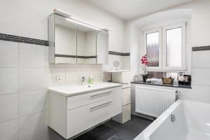 a white bathroom with a sink and a tub at Apartment In A Historic Villa in Stockach +31 photos