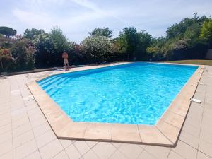 a man standing next to a large blue swimming pool at T2 duplex + piscine avec parking in Montpellier