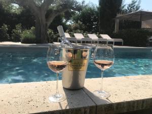 two glasses of wine sitting on a table next to a swimming pool at Villa La Begude - Boutique B&B in Saint-Tropez