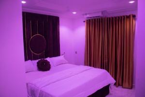 a bedroom with a large white bed with purple lighting at Star Haven Hotel and suites in Badore