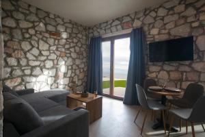 a living room with a couch and a stone wall at Nine Muses Hospitality in Nea Irakleia