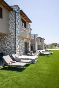 a lawn with lounge chairs and a building at Nine Muses Hospitality in Nea Irakleia