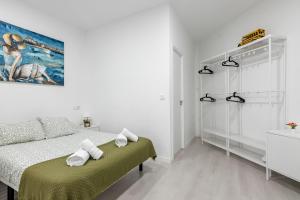 a white bedroom with a bed and a painting on the wall at Studio New Complete 4 pax in Madrid