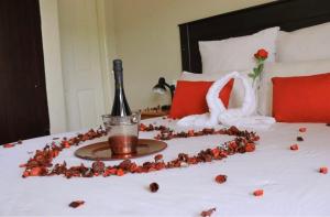 a bed with a bottle of wine and a rose petal at Boikhutsong Guest House in Maseru