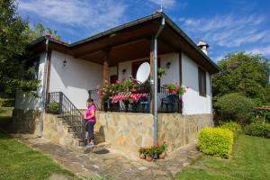a woman standing on the balcony of a house at къща Утринна Роса in Blŭskovtsi