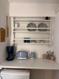 a kitchen shelf with plates and cups on it at Fotinos House Skiathos in Skiathos