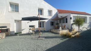 a patio with an umbrella in front of a house at Maison Mer Louis in Saint-Pierre-dʼOléron