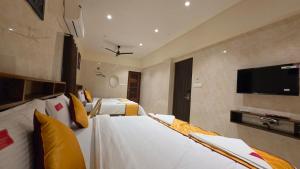 a hotel room with two beds and a flat screen tv at Kanchi Crown Residency in Kanchipuram