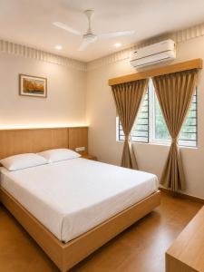 a bedroom with a large white bed and a window at Parthas Suites in Tiruchirappalli