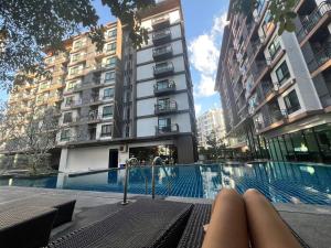 a woman laying on a bench next to a swimming pool at Living avenue condominuim in Ban Rong Khoei +4 photos