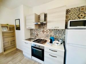 a kitchen with a white refrigerator and a microwave at Appartamenti Abbaidda in Valledoria