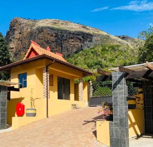 a yellow house with a mountain in the background at Ntaba Villas in Port St. Johns