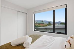 a bedroom with a large window and a bed with towels at Modern Lindisfarne Escape in Lindisfarne