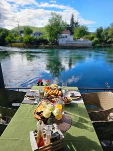 a table with food on it next to a body of water at Villa Hercegovački raj Elf in Blagaj