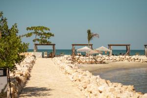 ein Strand mit Liegestühlen und Sonnenschirmen und das Meer in der Unterkunft Hotel Aimarawa in Coveñas