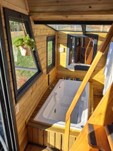 a tub in a tiny house with two windows at Vale do Sossego- Cabana na Serra in Alfredo Wagner