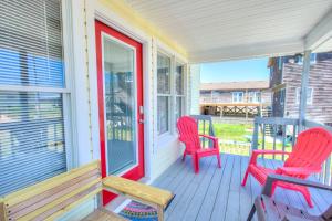 a porch with two chairs and a red door at 4073 - Downtime in Kitty Hawk
