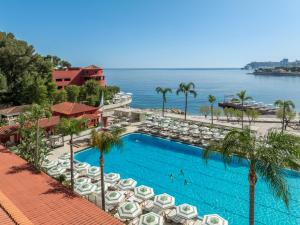 a resort swimming pool with umbrellas and the ocean at Monte-Carlo Beach in Roquebrune-Cap-Martin
