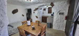 a kitchen with a wooden table in a room with white walls at Cuevita El Abrigo - 1 dormitorio in Lomo de Arico