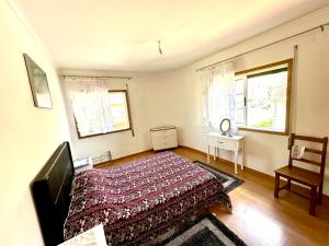 a bedroom with a bed and a chair and two windows at Quarto em Bragança in Bragança