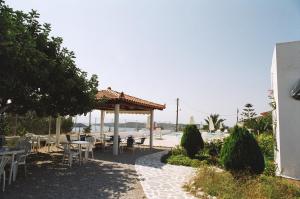 a patio with tables and chairs and a pavilion at Long View Apartments in Porto Heli