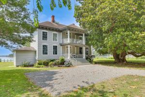 a white house with a porch and a tree at Waterfront Home with Large Yard, Dock & Bay View in Heathsville