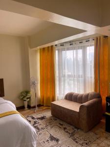 a bedroom with a couch in front of a window at Pendo suite in Nairobi