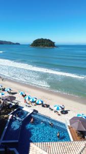 a view of a beach with a swimming pool and umbrellas at Kaliman Pousada in Ubatuba