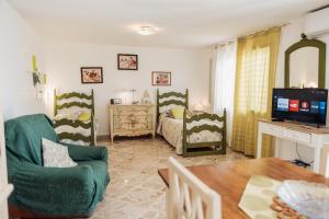 a living room with a bed and a tv and a table at Casa Bianca Rais Gerbi in Finale