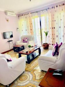 a living room with white chairs and a coffee table at Esther properties in Entebbe