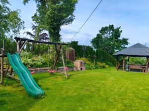 a playground with a green slide in a yard at Wczasy z Wędką in Gardna Wielka
