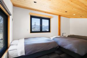 two beds in a room with a window at New Field Chalet 白馬 in Hakuba +21 photos