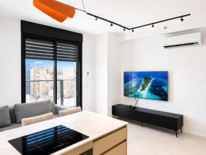 a living room with a couch and a tv on a wall at Apartments4you Queen in Bat Yam