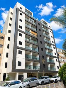 a tall building with cars parked in front of it at Apartments4you Queen in Bat Yam