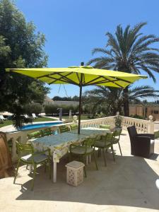 a table and chairs under a yellow umbrella next to a pool at Darelkhir in Tazarka