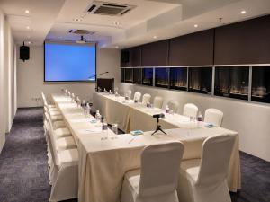 a conference room with white tables and chairs and a screen at deKing Hotel Twin Towers by DK Hospitality in Kuala Lumpur