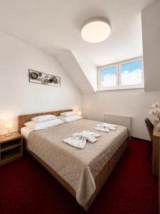 a bedroom with a large bed with towels on it at Hotel Evan u Hoffera with free parking in Topoľčany