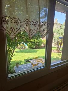 a window with a table and a bench in a yard at Gîte 3 "le Canal de Baza" aux Magnolias in Aubenas