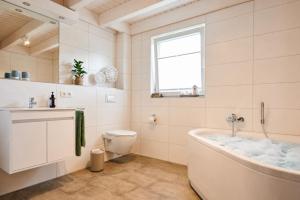 a bathroom with a tub and a toilet and a window at Huus Sünnschien - Nordhorn in Nordhorn