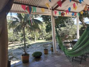 a patio with a hammock and a palm tree at Abelha & Peixe Boi in Santo Amaro