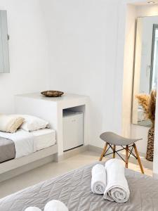 a white bedroom with a bed and a chair at Fira Centrum White in Fira