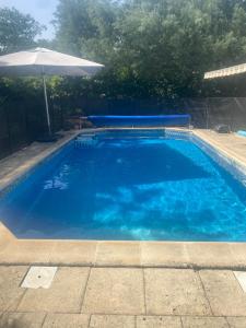 a large blue swimming pool with an umbrella at Charmant studio in Saint-Aubin-de-Médoc
