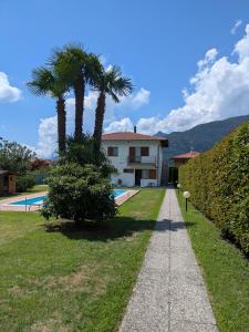 a house with two palm trees and a sidewalk at Casa Augusta in Maccagno Superiore
