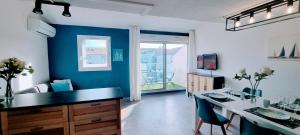 a kitchen with a table and a blue wall at L'Ophelia Duplex Dernier étage balcon Centre climatisation in Sète
