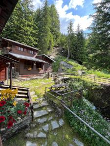 a house with a pathway leading to a yard with flowers at Baita Pòz in Valfurva