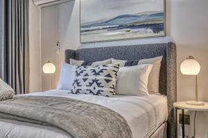 a bedroom with a white bed with two lamps at Stormside at Ellipse in Midrand +9 photos