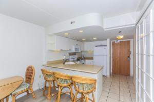 a kitchen with a counter and chairs and a table at Ilikai Tower 1403 in Honolulu