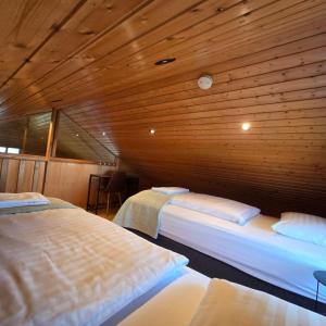 two beds in a room with wooden walls at Akureyri Cottages in Akureyri
