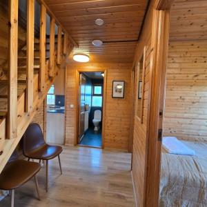 a room with wooden walls and a staircase with a bed and chairs at Akureyri Cottages in Akureyri +24 photos