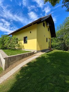 a yellow house with a grass yard at Digital Detox House Haloze in Podlehnik